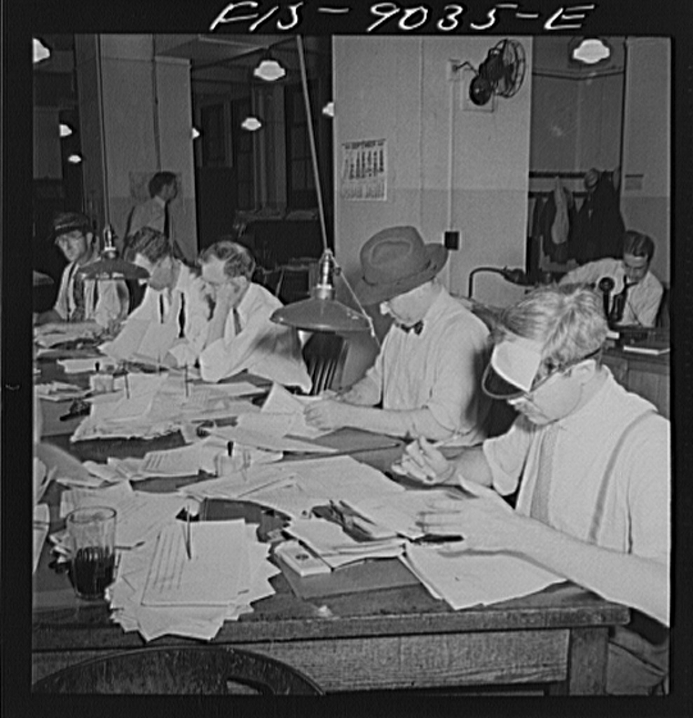 Editors working together at a historic newsroom desk